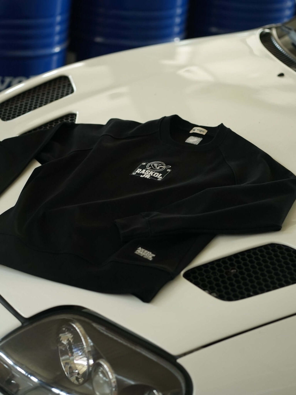 Raskol JR. Gece Siyah Sweatshirt laid over a white car hood, showcasing its stylish design and fabric details.
