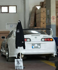 Raskol JR. Gece Siyah Sweatshirt hanging beside a white Toyota Supra in an industrial setting.