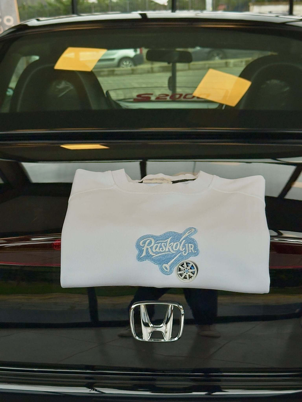 Raskol JR. Ekru Beyaz Mavi Denim&Jant Detaylı Sweatshirt folded on the trunk of a Honda.
